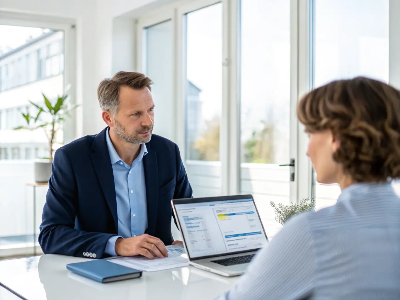 A professional financial advisor is sitting at a desk, reviewing financial documents with a client in a modern office setting. The scene conveys trust, expertise, and personalized service.
